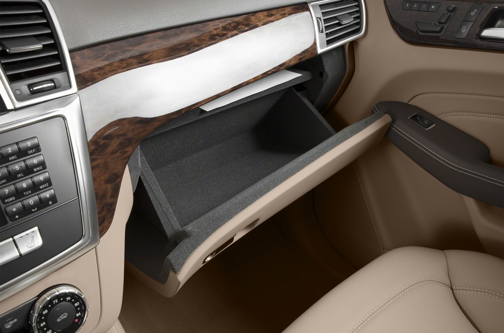 Open glove compartment with wood trim and beige leather interior