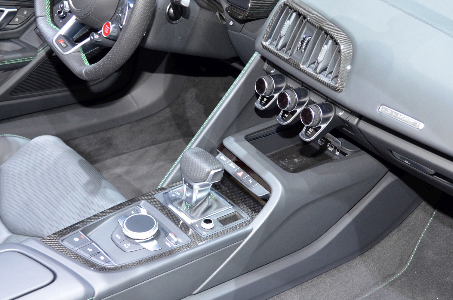 Close-up of center console, gear shifter, and climate controls with carbon fiber accents
