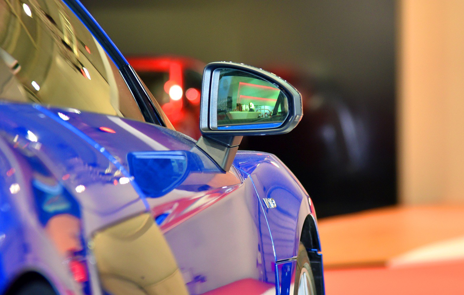 Close-up of side mirror and smooth aerodynamic blue car body