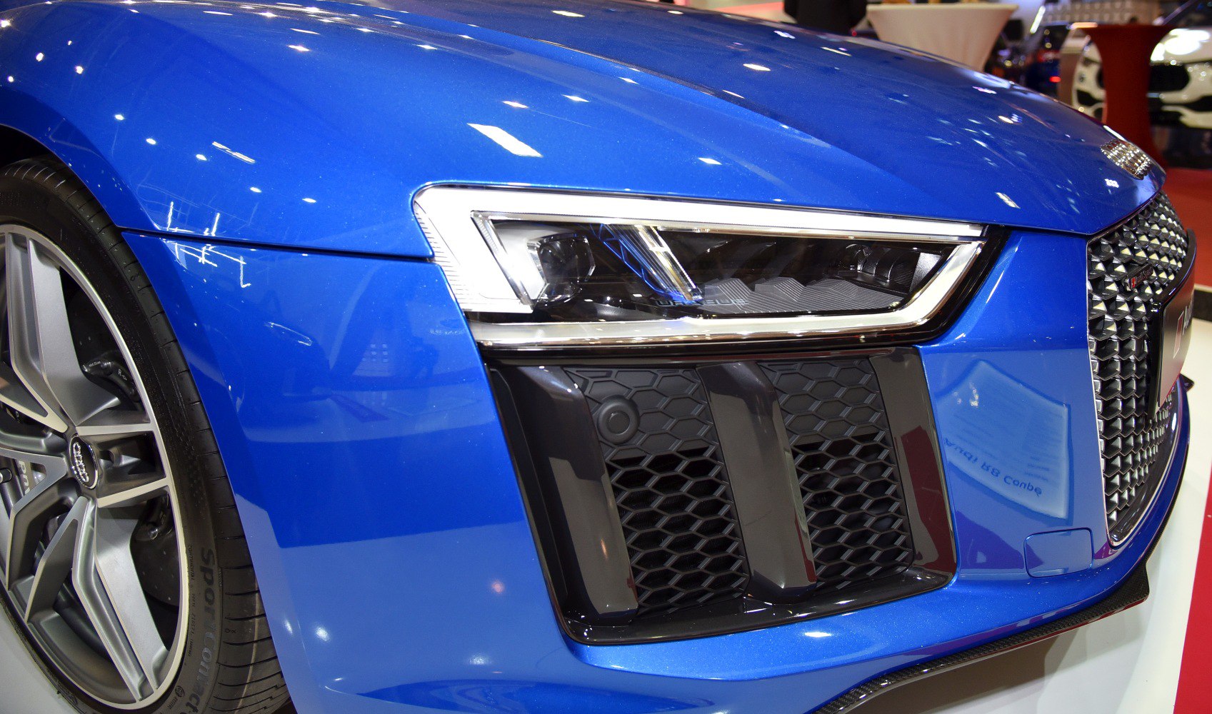 Close-up of a car's front headlight and wheel in blue