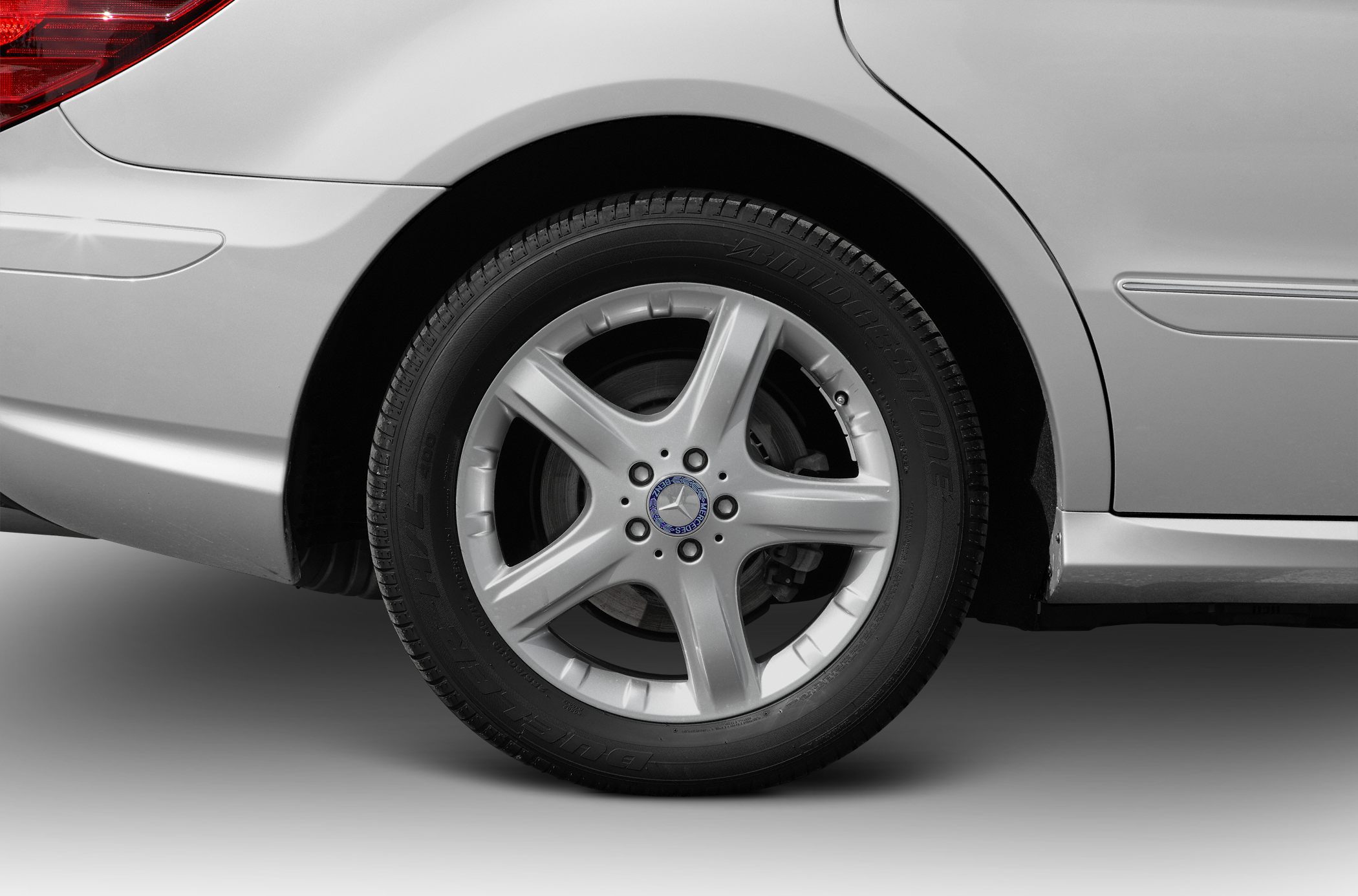 Close-up of a silver five-spoke alloy rear wheel and Bridgestone tire on a vehicle.