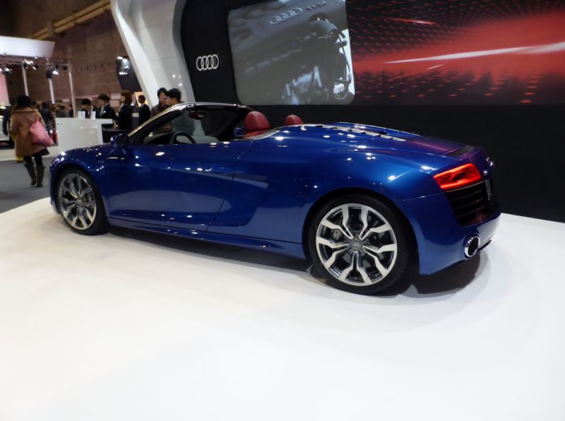 Side and rear view of a blue convertible sports car with modern wheels.