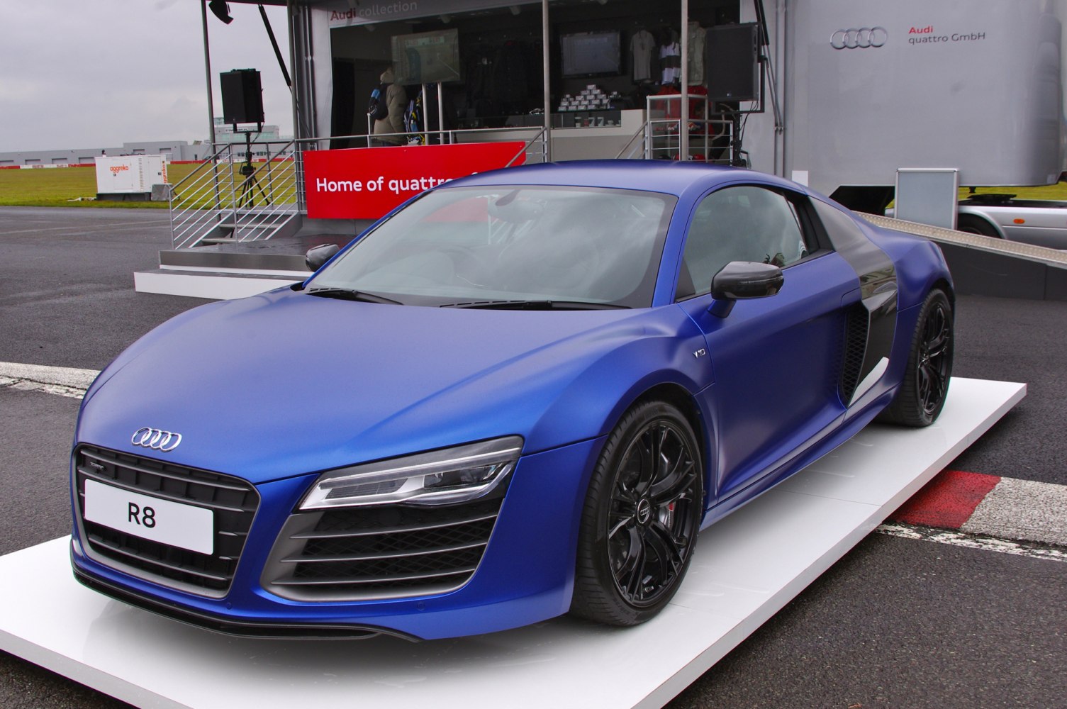 Front-side view of a matte blue sports coupe with black alloy wheels and aerodynamic styling