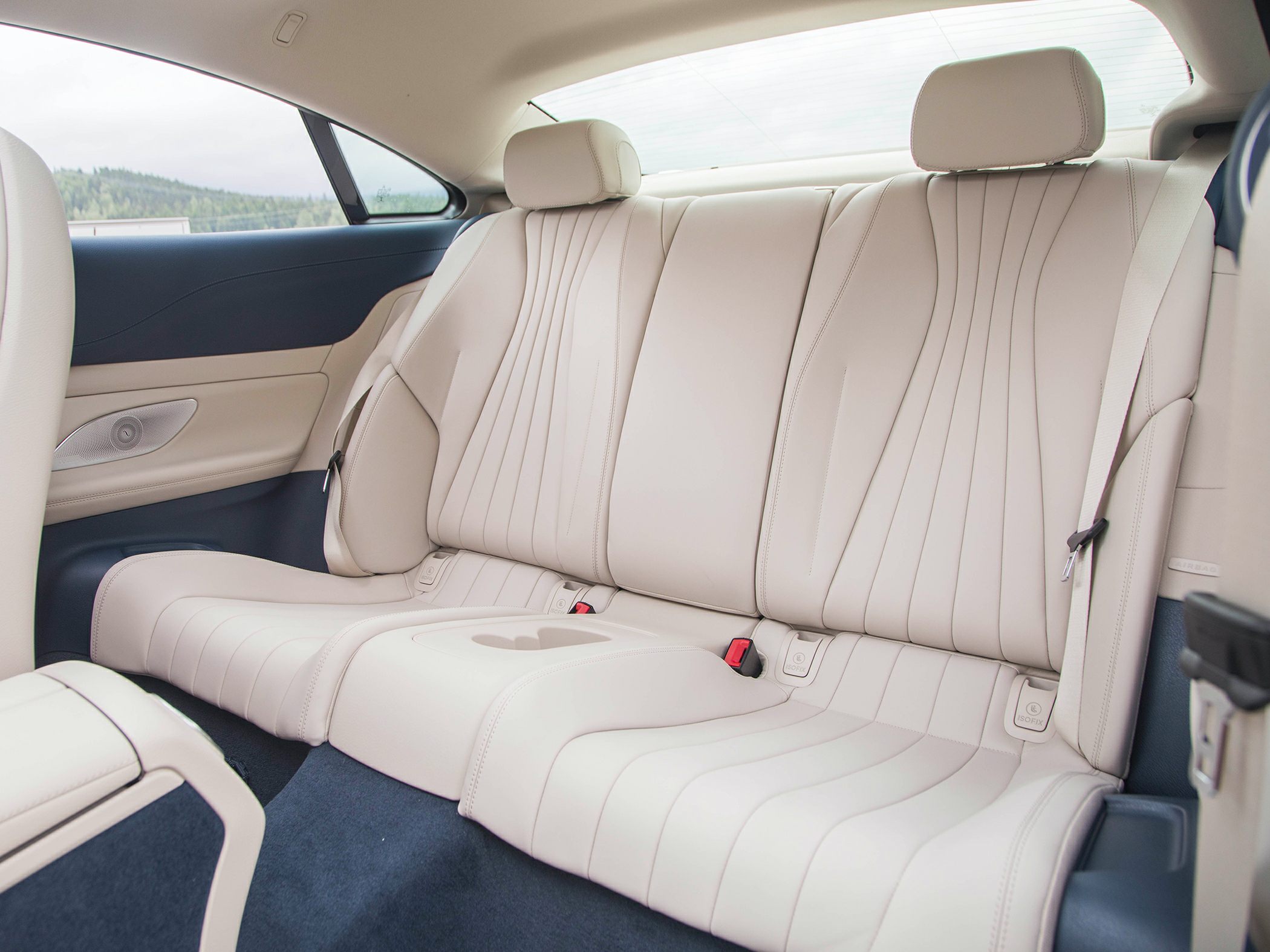Beige leather rear seats with detailed stitching and built-in cupholder console