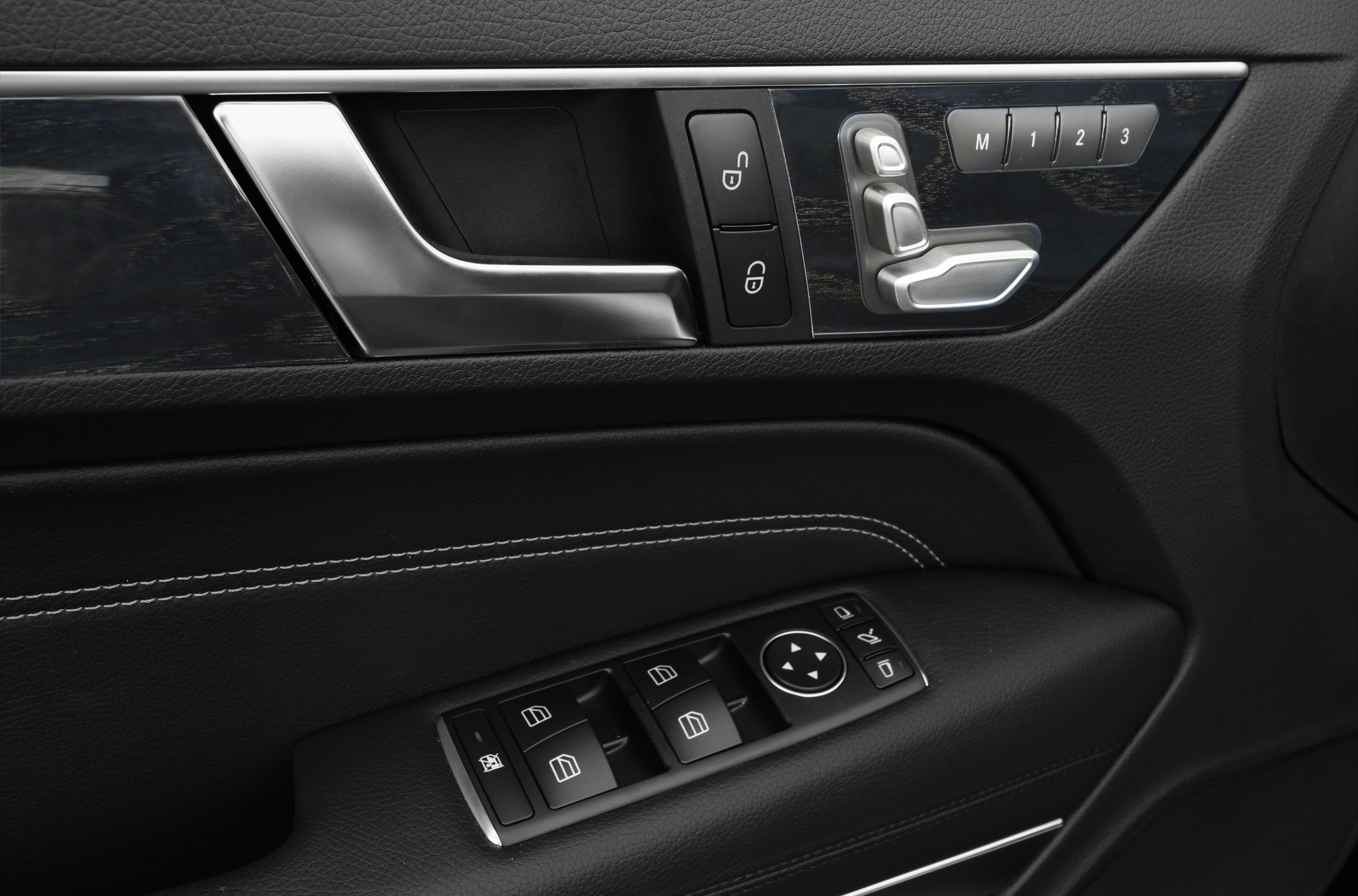 Door panel with seat adjustment and window control buttons, leather trim, and stitching.