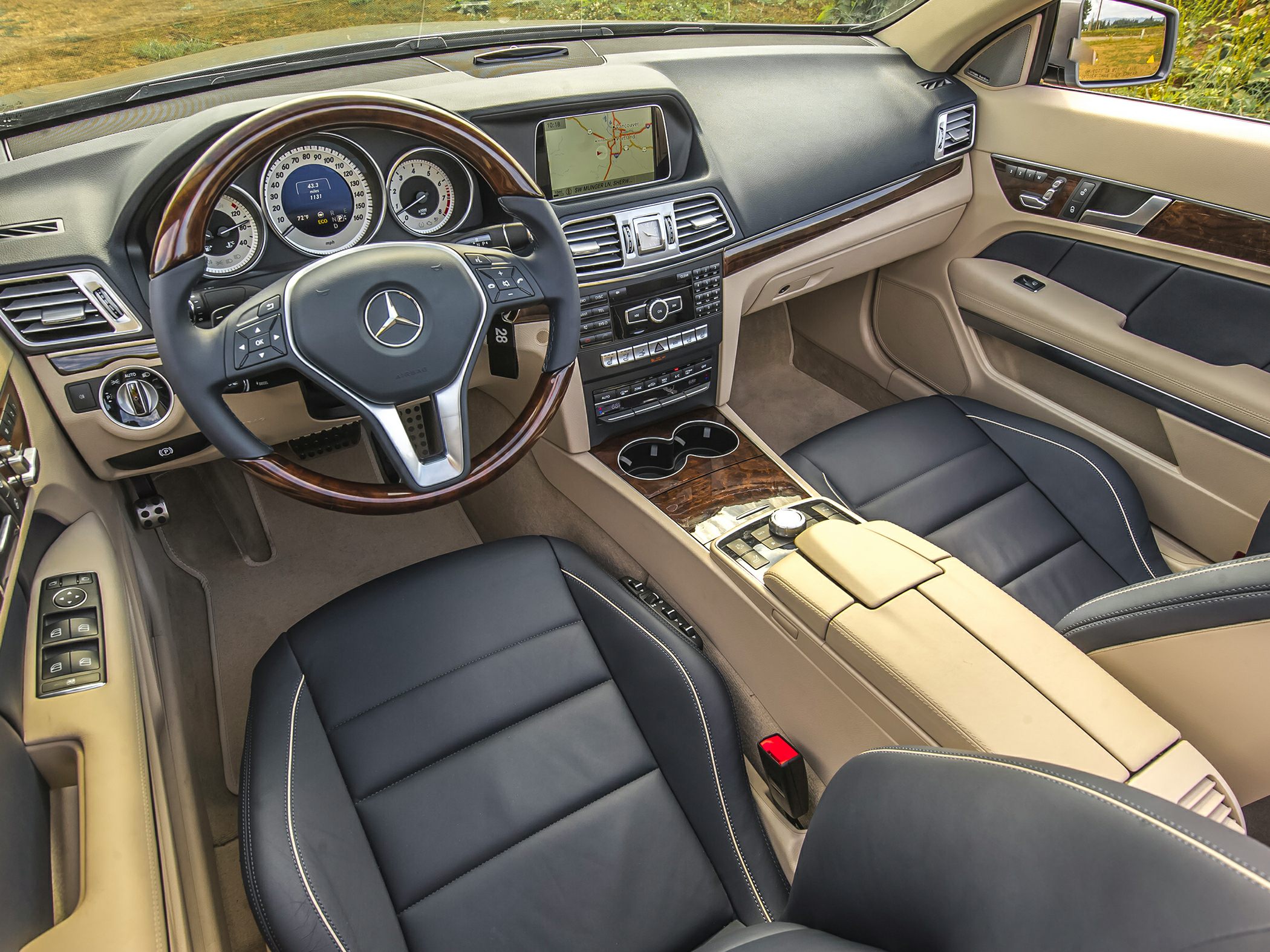 Luxury dashboard with wood-trimmed steering wheel and beige-black leather interior