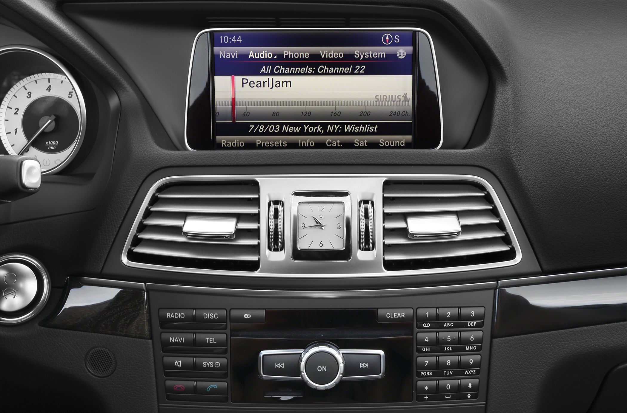 Infotainment screen, analog clock, dual air vents, media control buttons