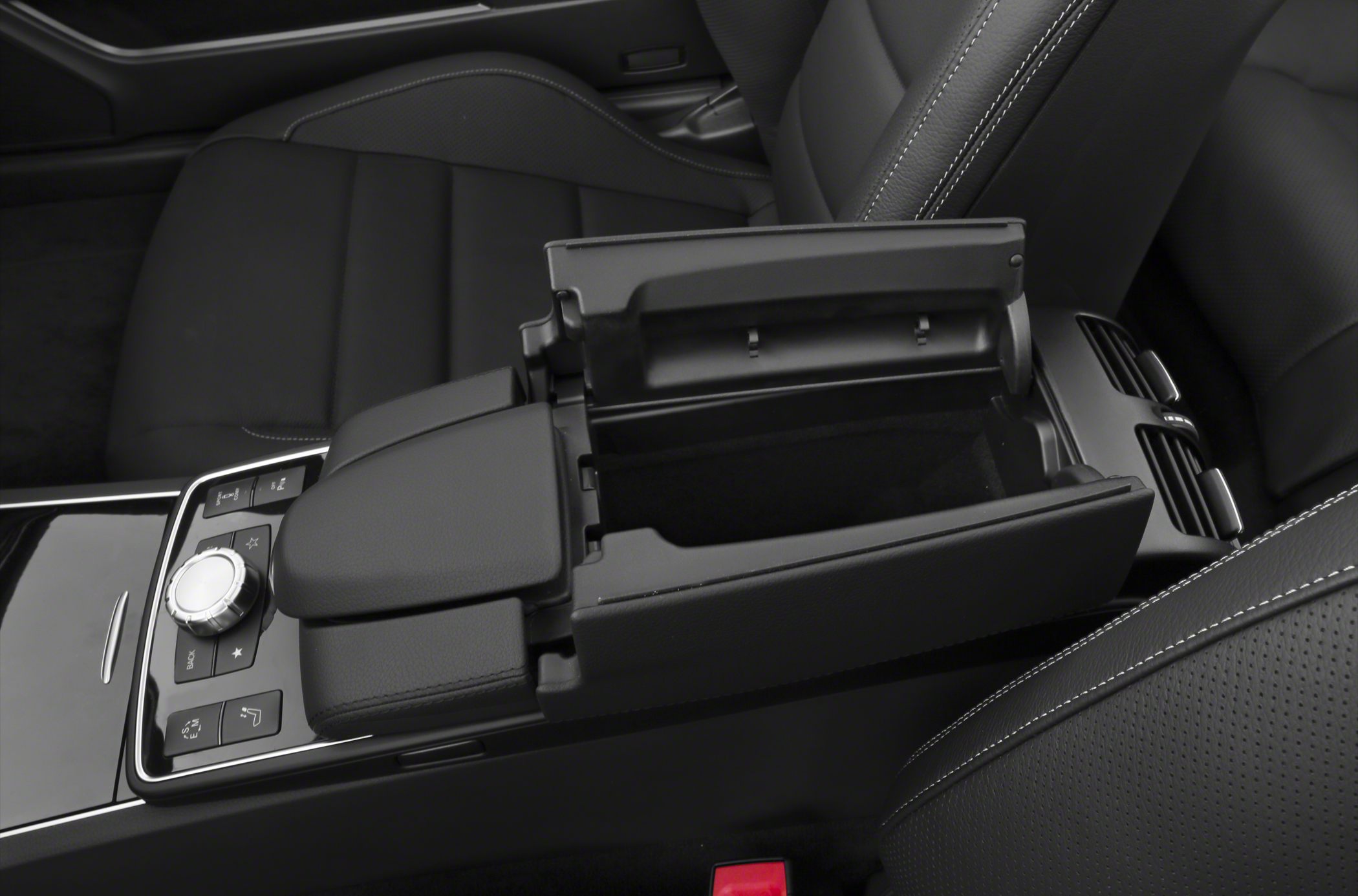 Open center console compartment with rotary control knob and seat detail