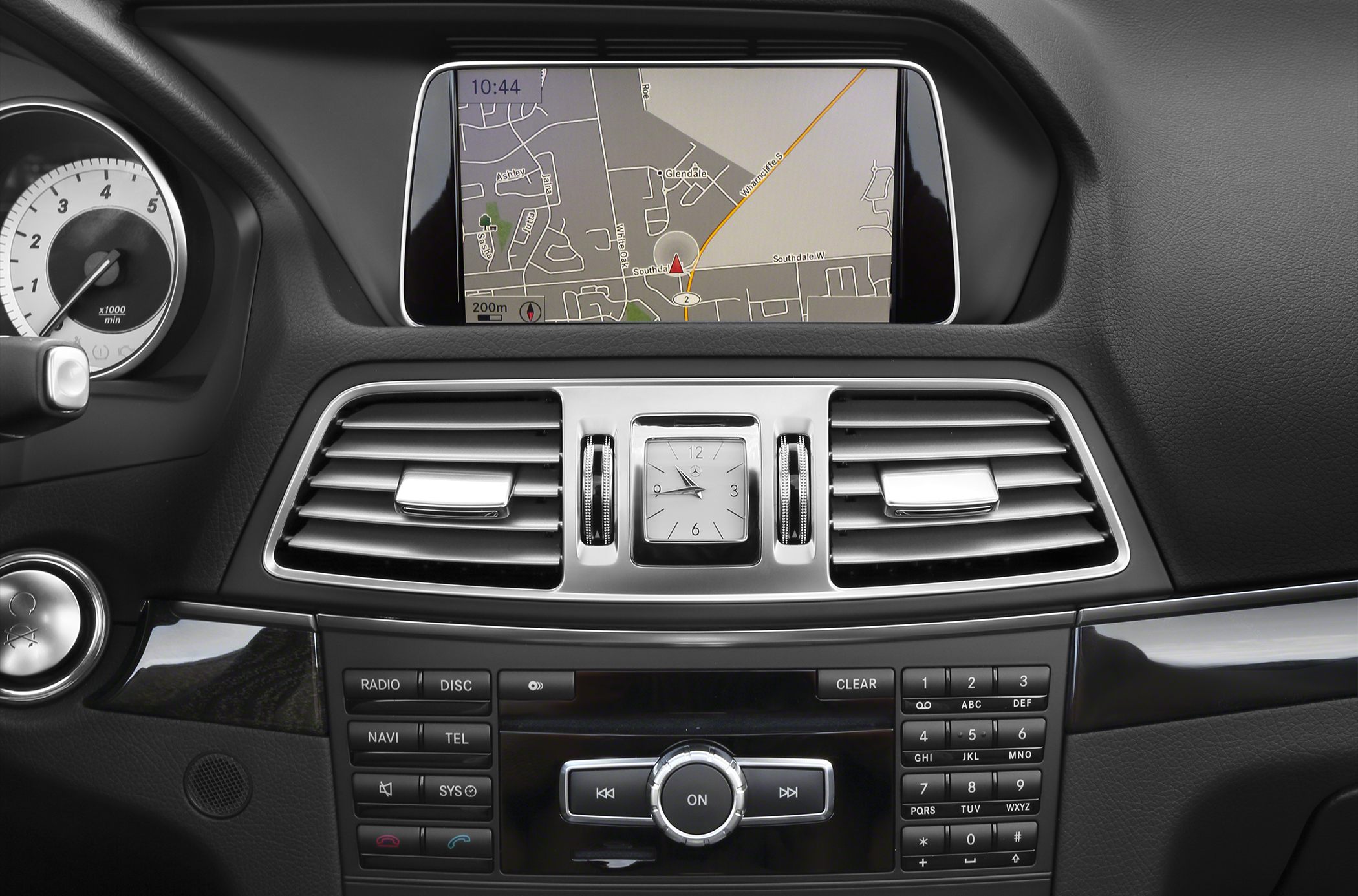 Infotainment system screen and analog clock on a luxury car dashboard