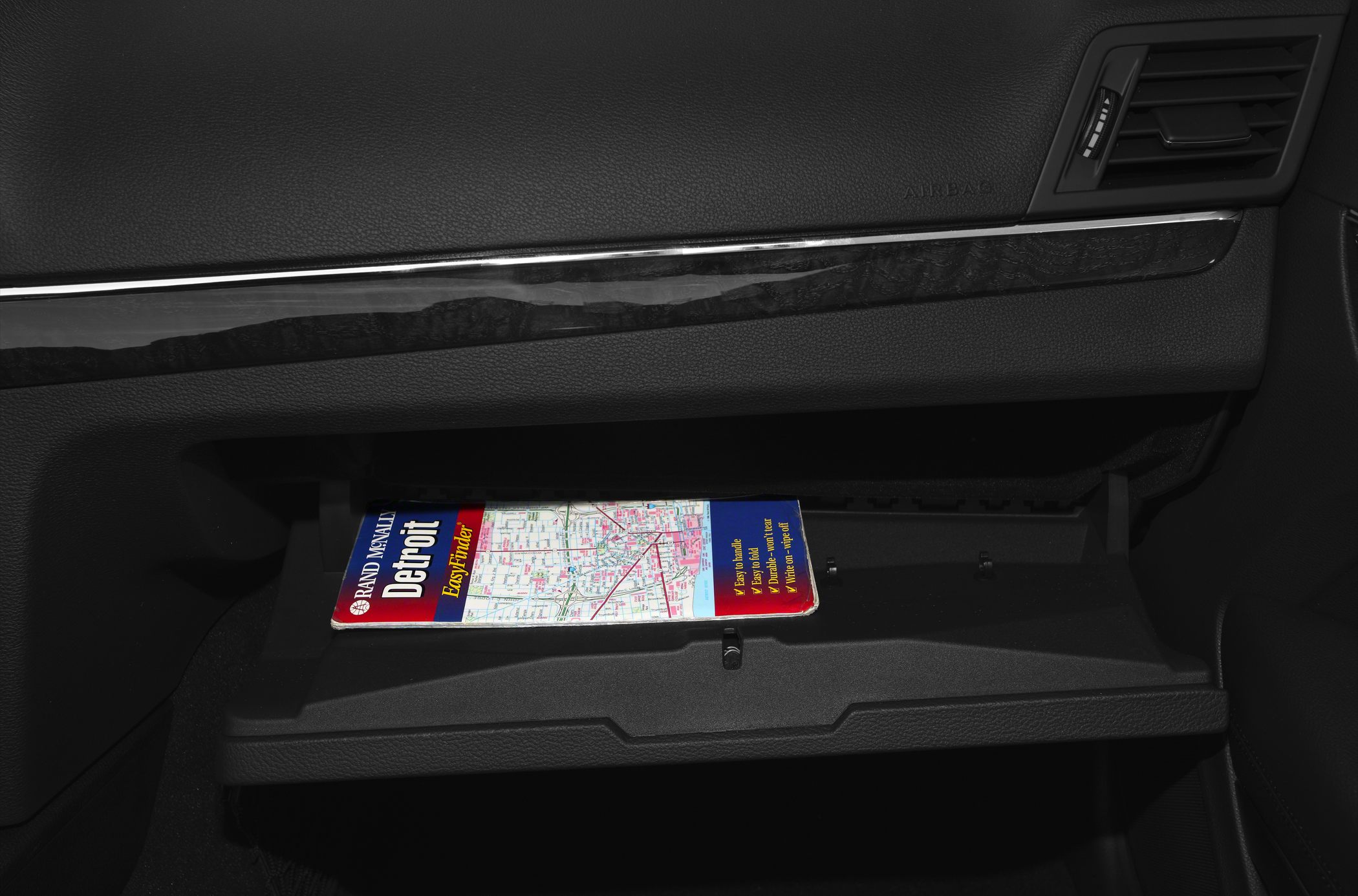 Car dashboard and open glove compartment with a map inside