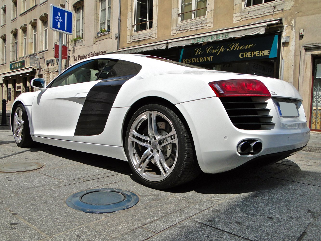 Rear side view of white sports coupe with dual exhaust and distinctive side blade