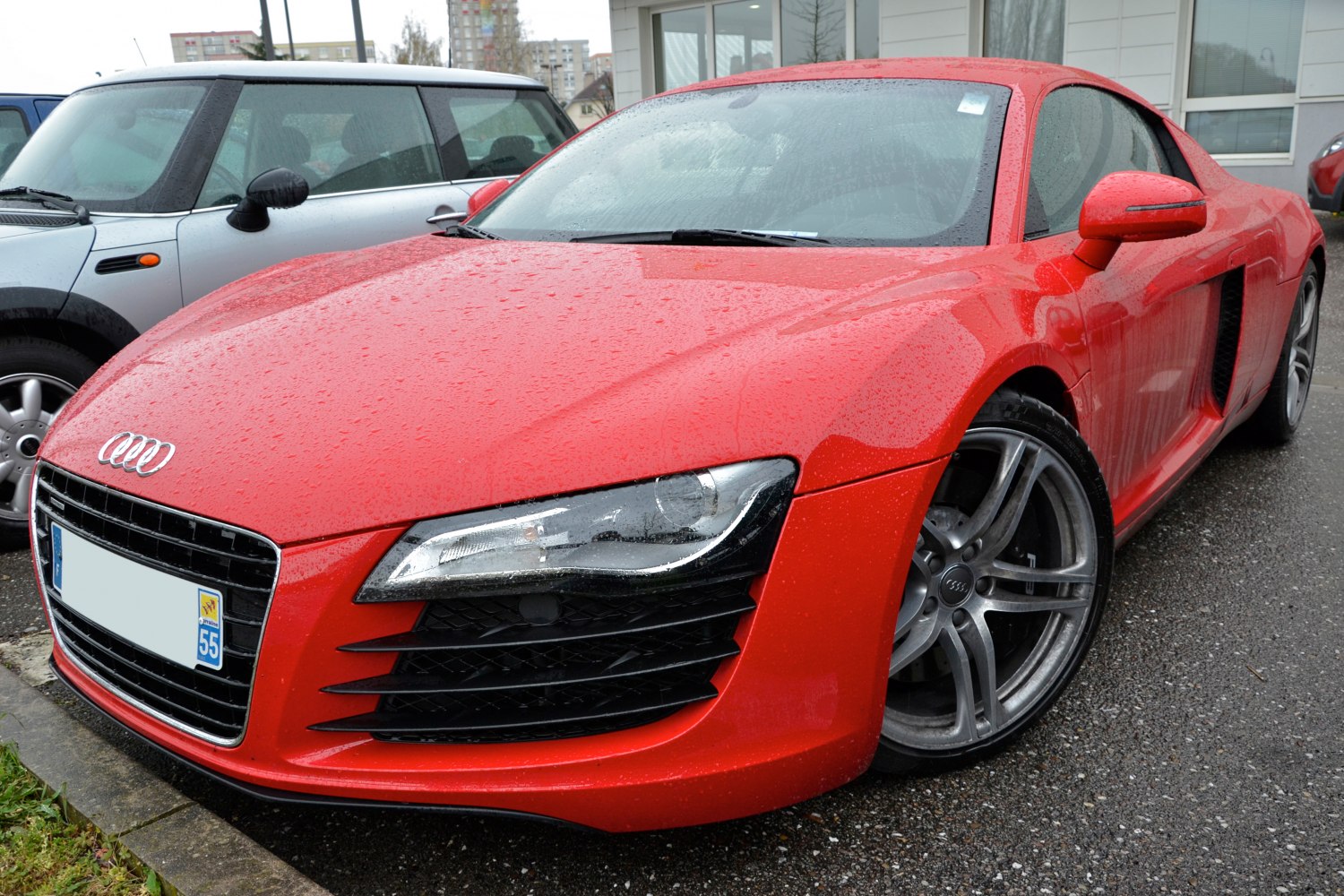 Red sports coupe front with distinctive headlights and alloy wheels