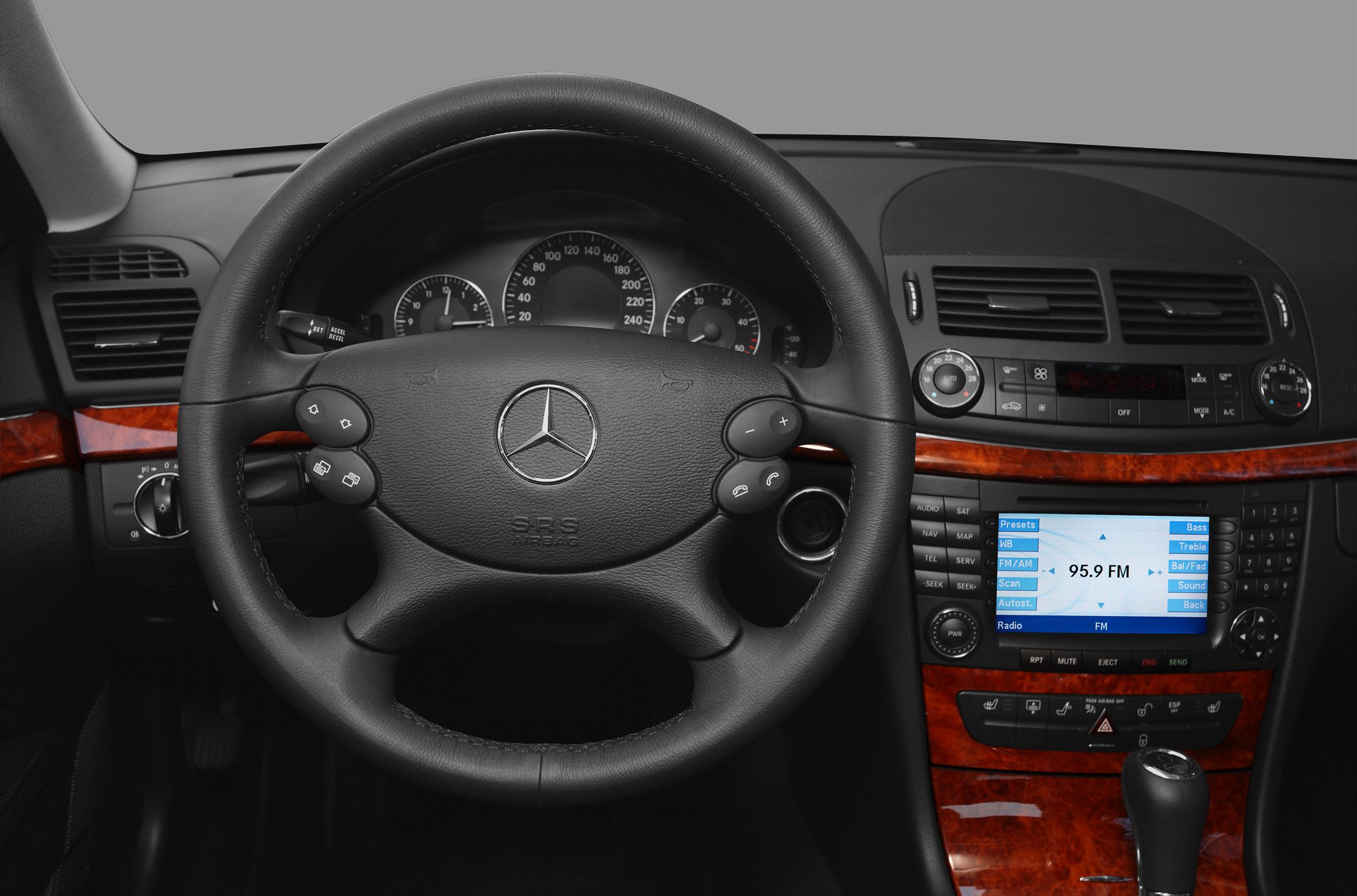 Interior view of steering wheel and dashboard with infotainment and wood trim