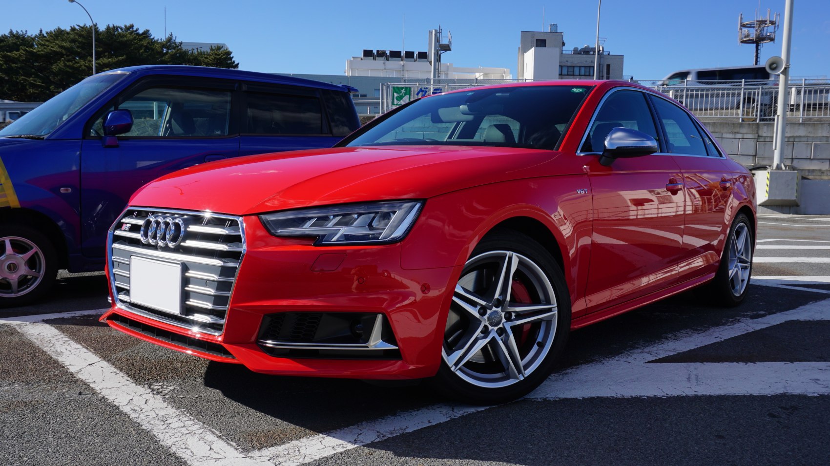 Front grille and alloy wheels of a red sedan
