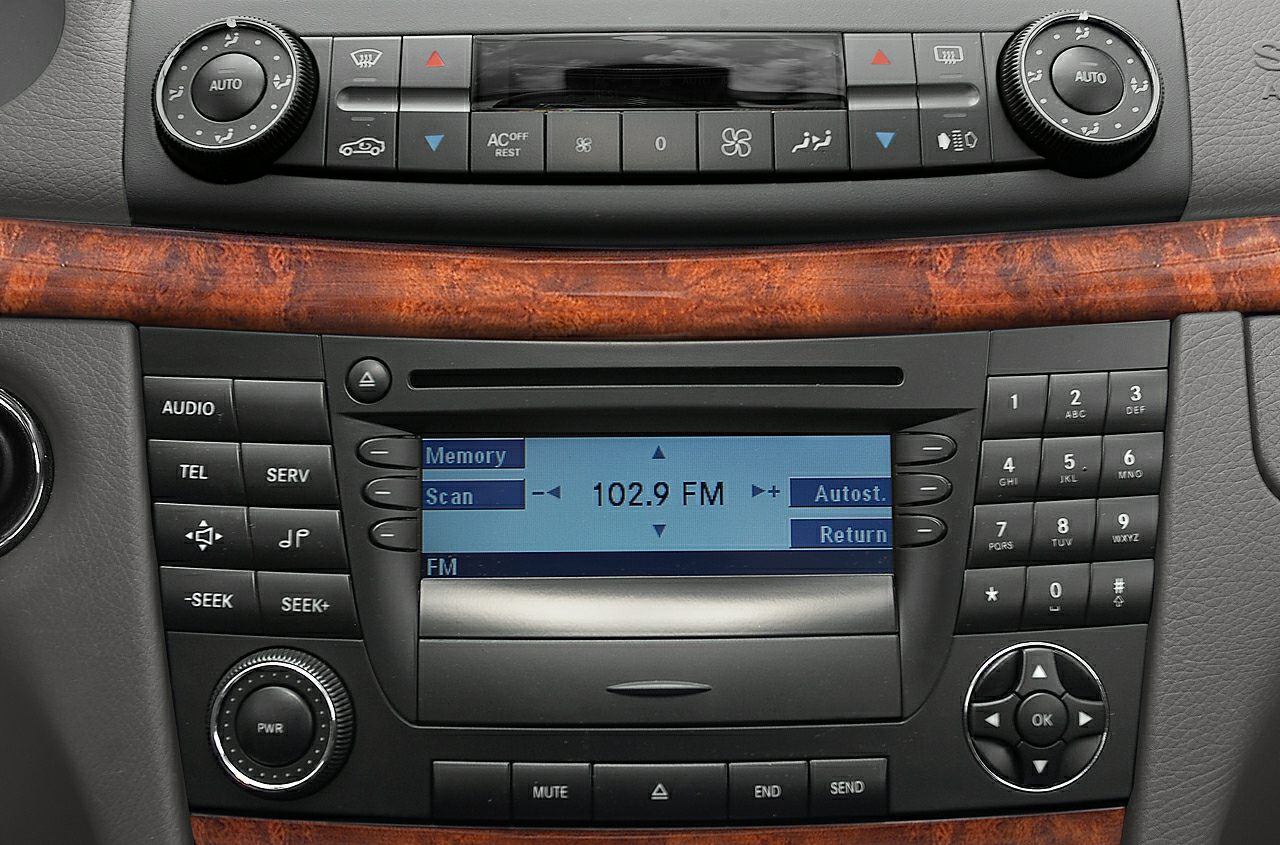 Car radio and climate control panel with FM display and wood trim.