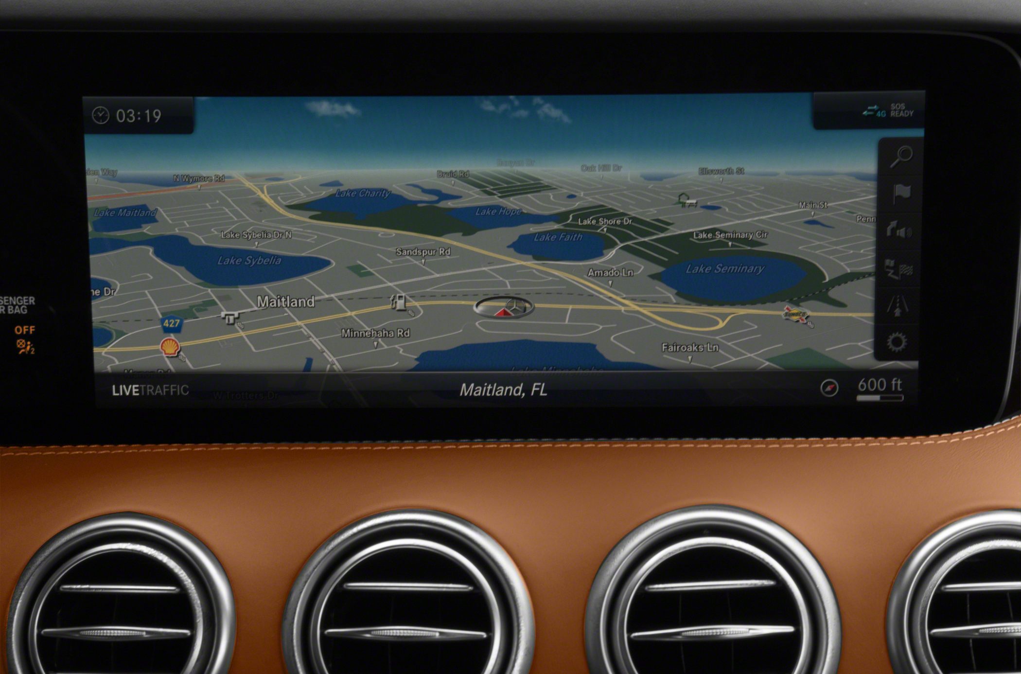 Digital navigation display with live traffic and four circular air vents on brown dashboard