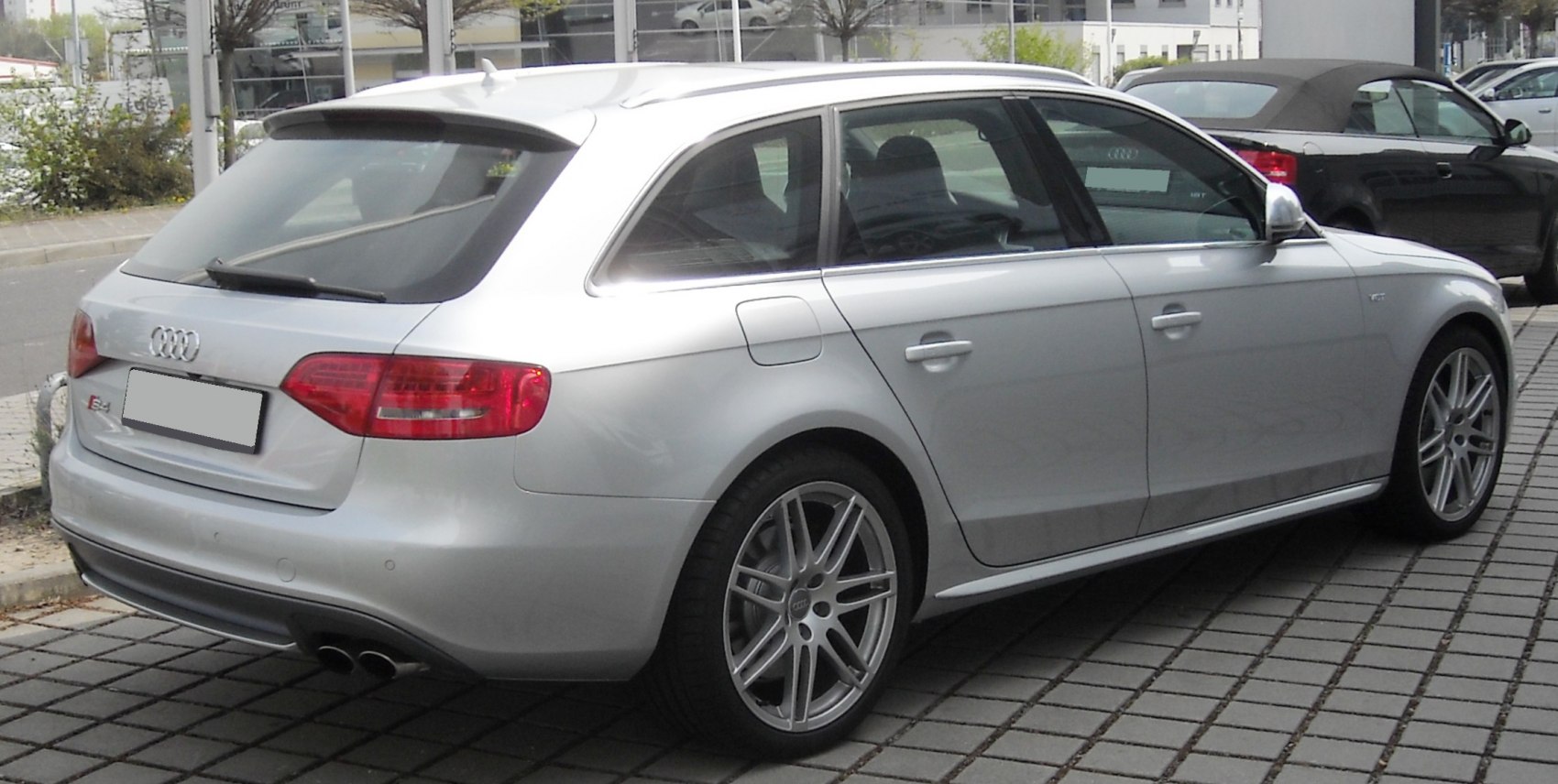 Silver metallic station wagon showing rear and side profile with alloy wheels and dual exhaust