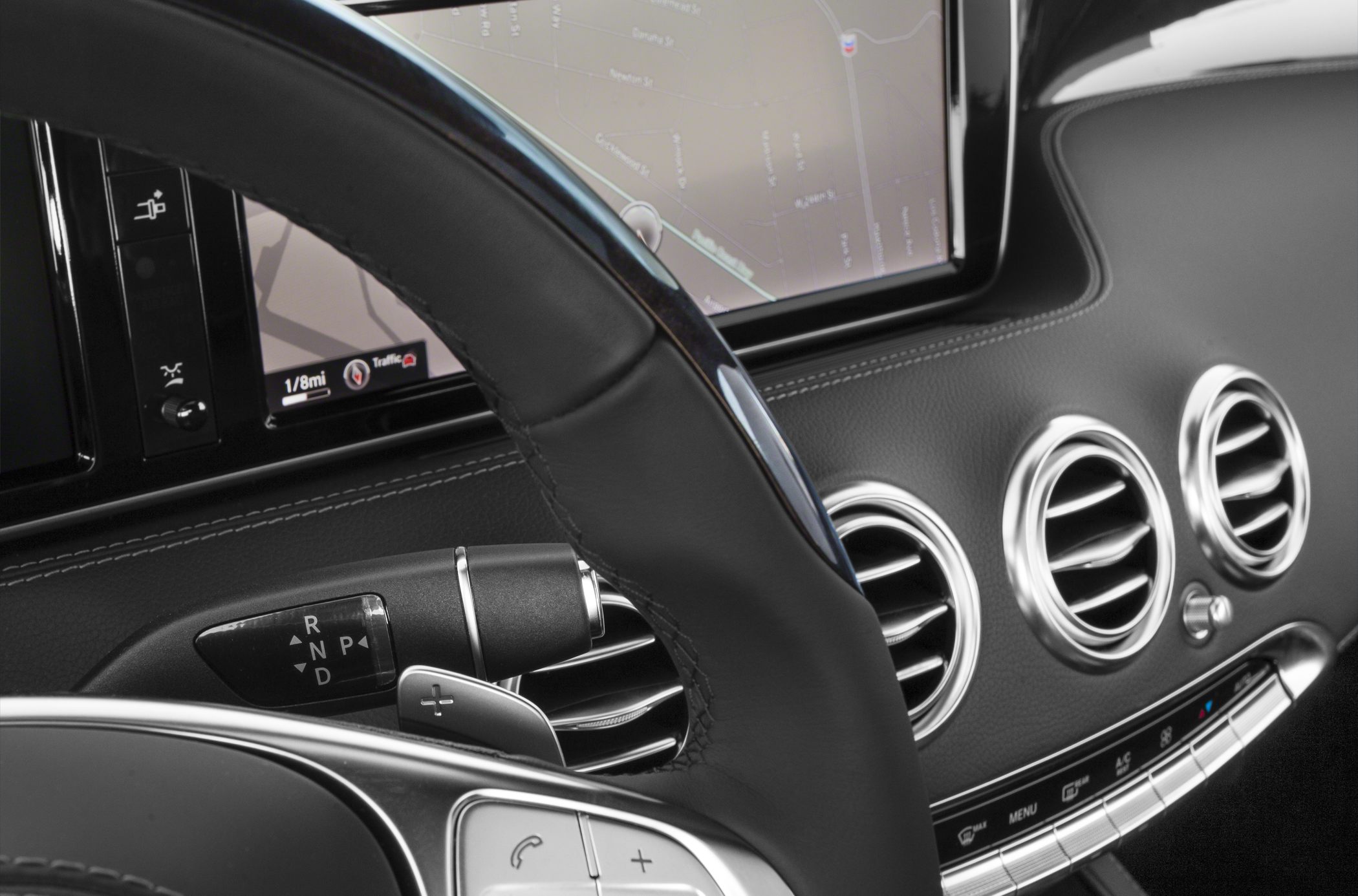 Steering wheel, gear selector, round air vents, and navigation infotainment screen