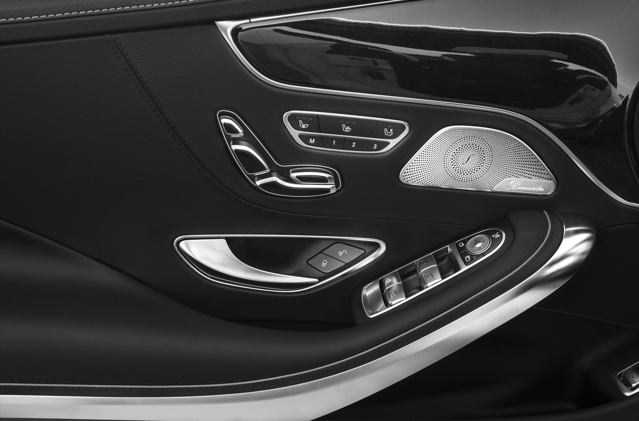 Luxury car door panel with seat controls and premium sound speaker