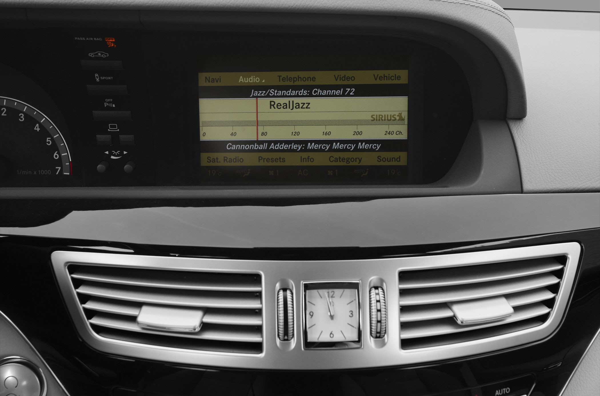 Infotainment screen and analog clock with air vents in dashboard