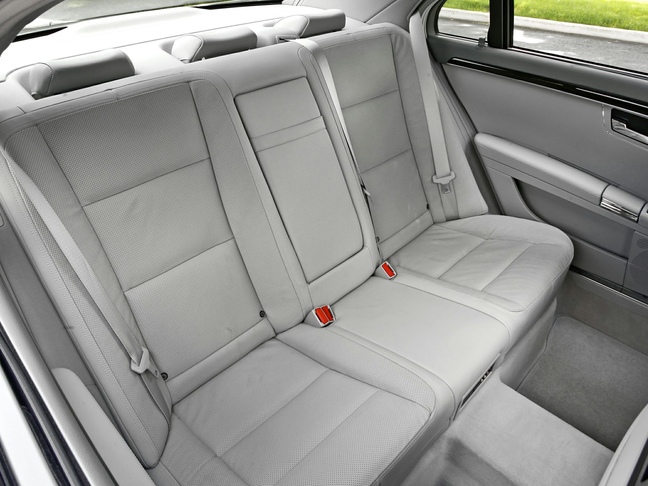 Rear seat interior with perforated leather upholstery and seat belts.