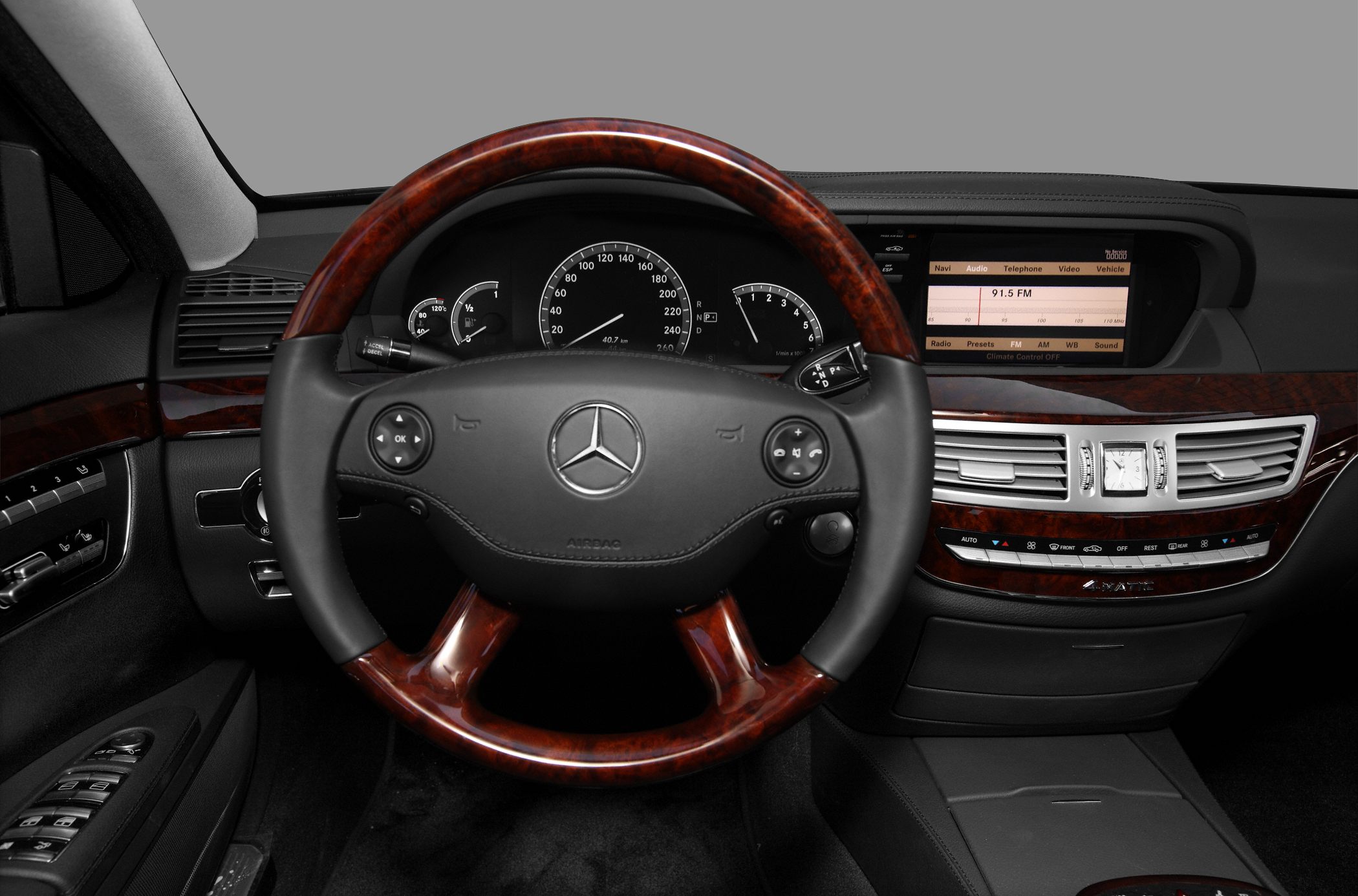 Wood-trimmed steering wheel and elegant dashboard with digital display and analog gauges.