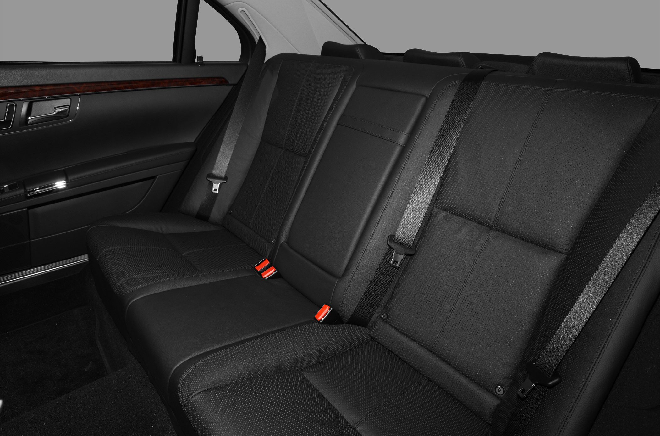 Black leather rear seats with integrated seat belts and wood trim.