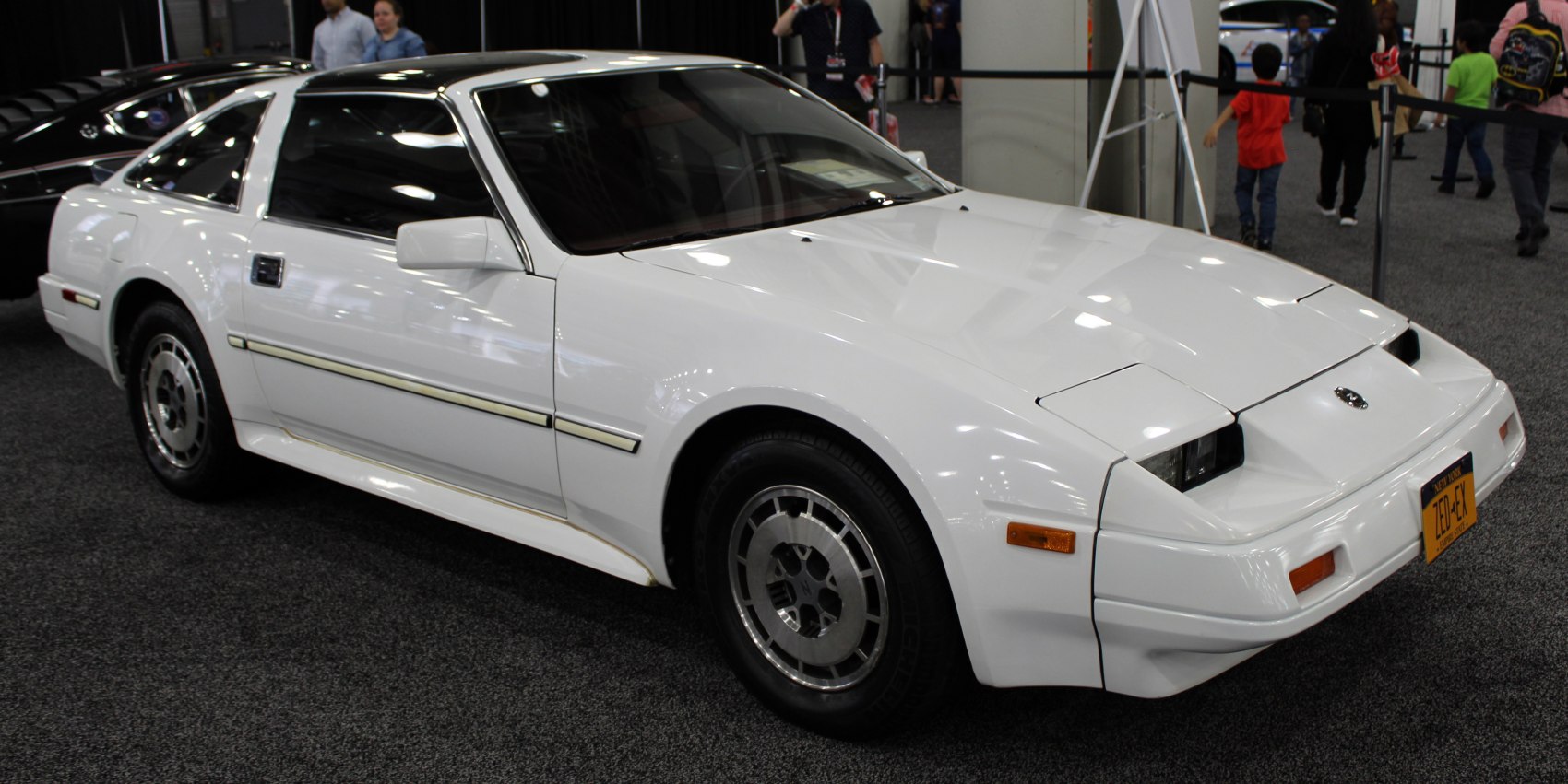1980s white sports coupe with pop-up headlights and T-top roof