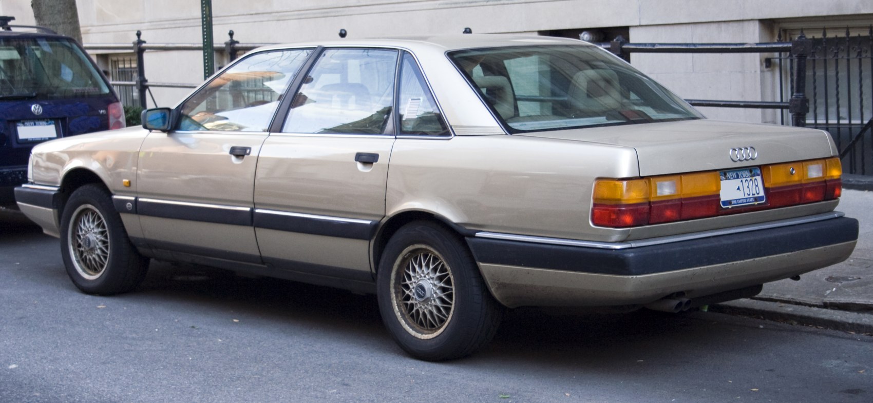 Classic sedan rear-side view with mesh alloy wheels and amber-red taillights