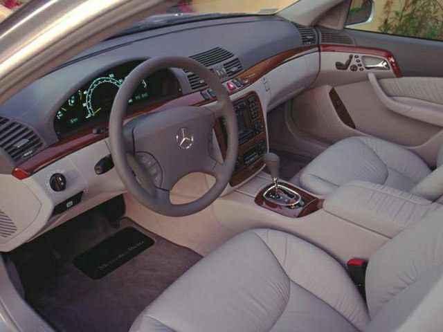 Luxurious dashboard and beige leather seats with wood trim and automatic gear shifter.