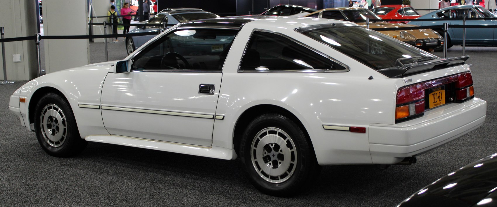 Side and rear view of a white angular sports coupe with rear spoiler and distinctive wheels