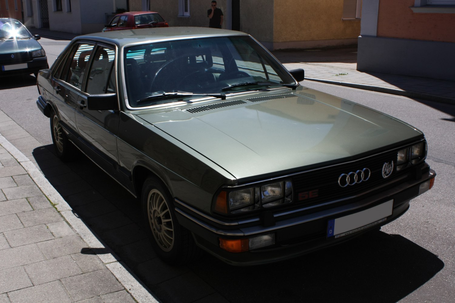 Classic sedan front and side view with quad headlights and vintage alloy wheels