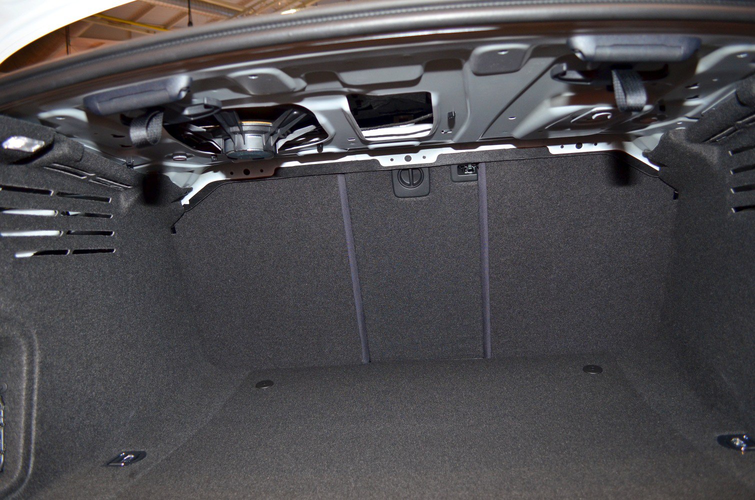 Spacious carpet-lined rear trunk interior with visible latch and hooks
