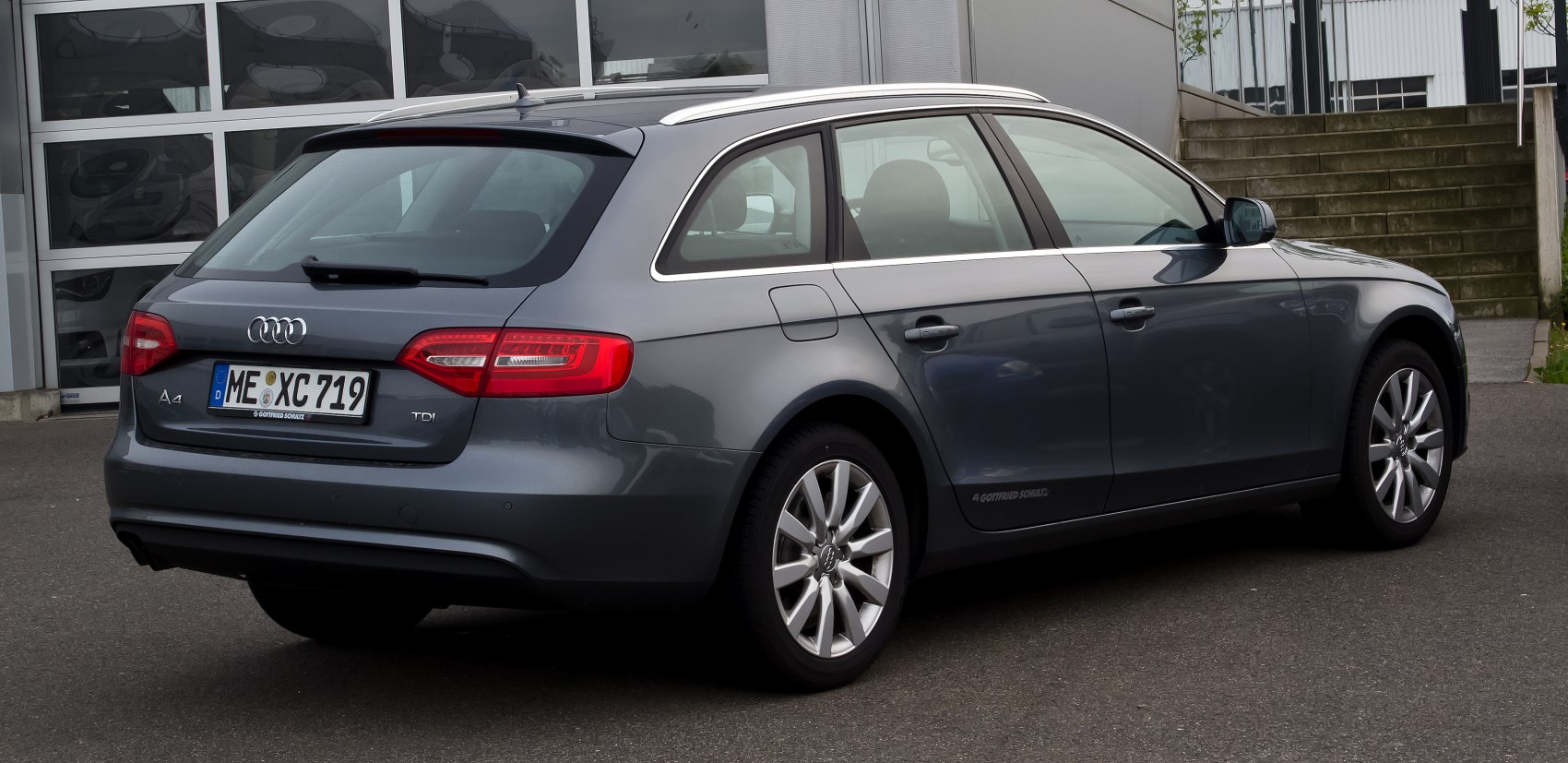 Rear view of a gray station wagon with distinctive taillights and silver roof rails