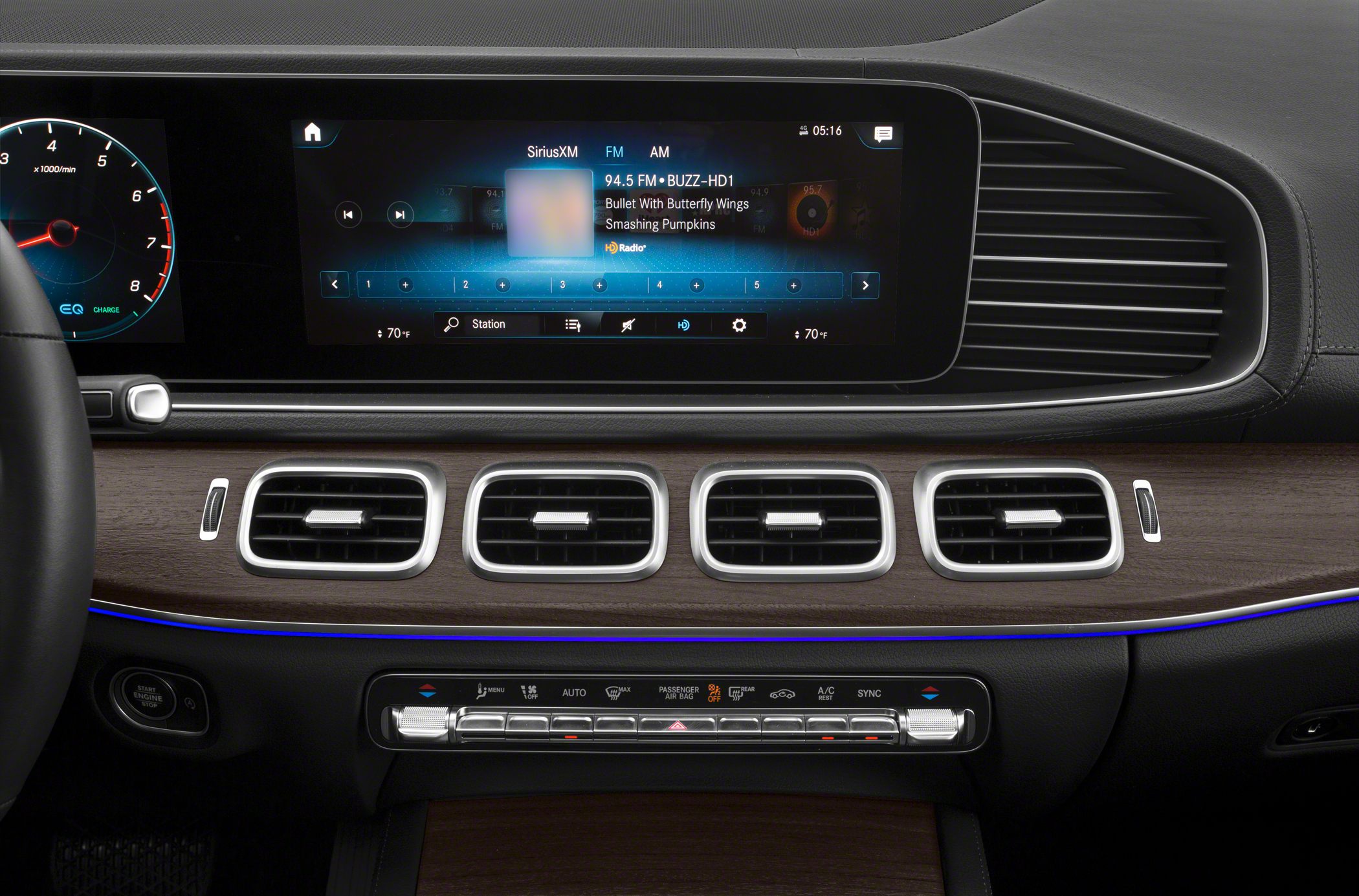 Digital infotainment screen and rectangular air vents with wooden trim.