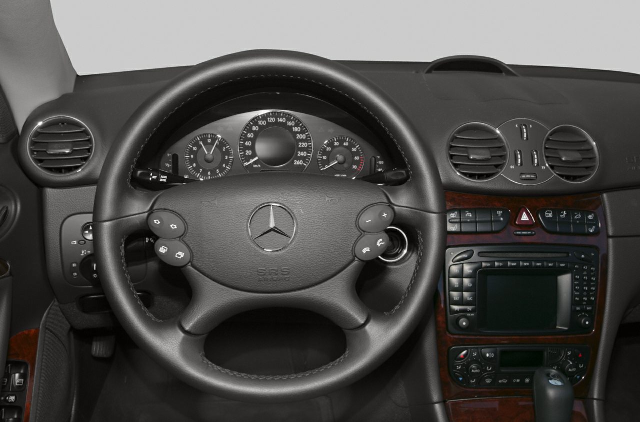 Steering wheel with control buttons and dashboard with wood trim and instrument cluster