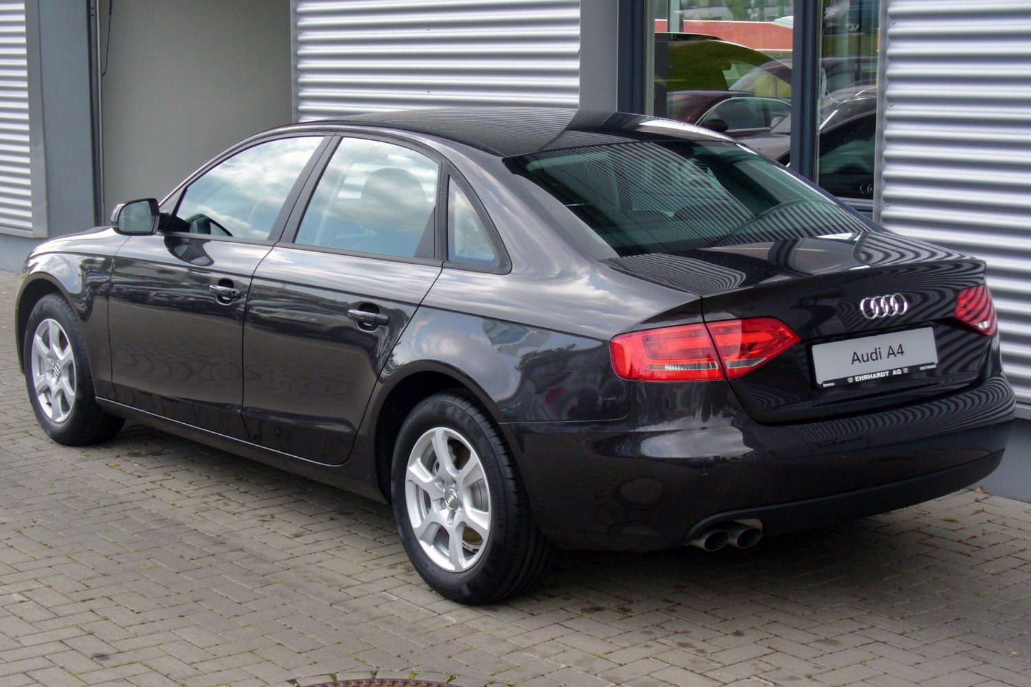 Rear side view of black sedan with alloy wheels and dual exhaust pipes
