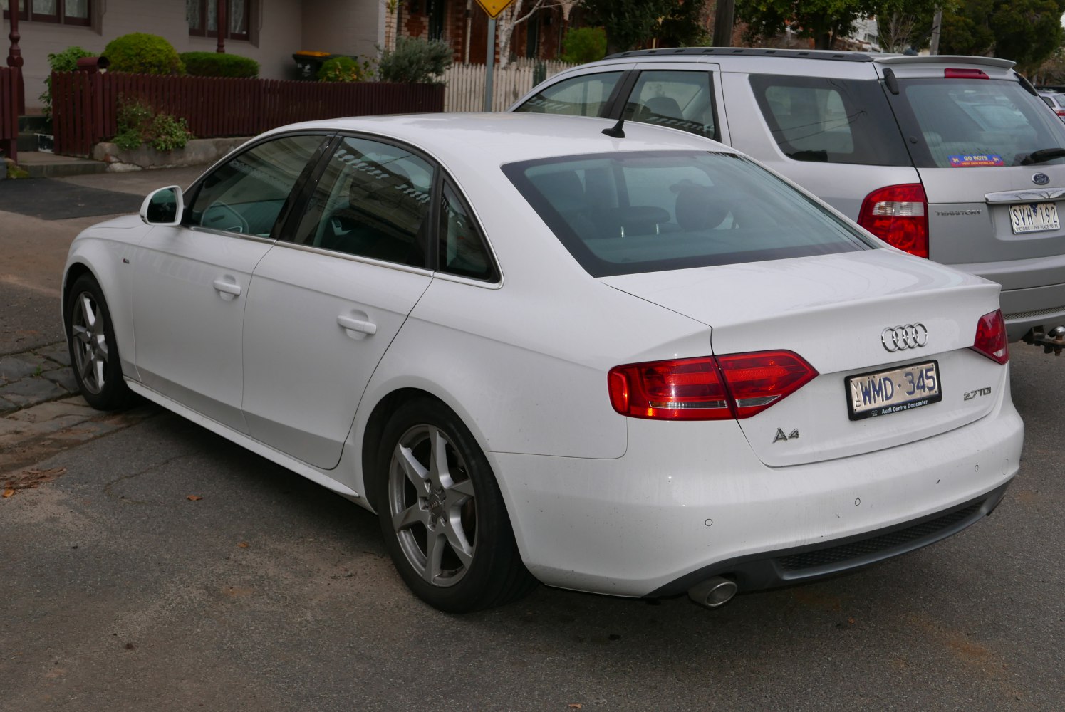 White sedan rear and side view with taillights and alloy wheels