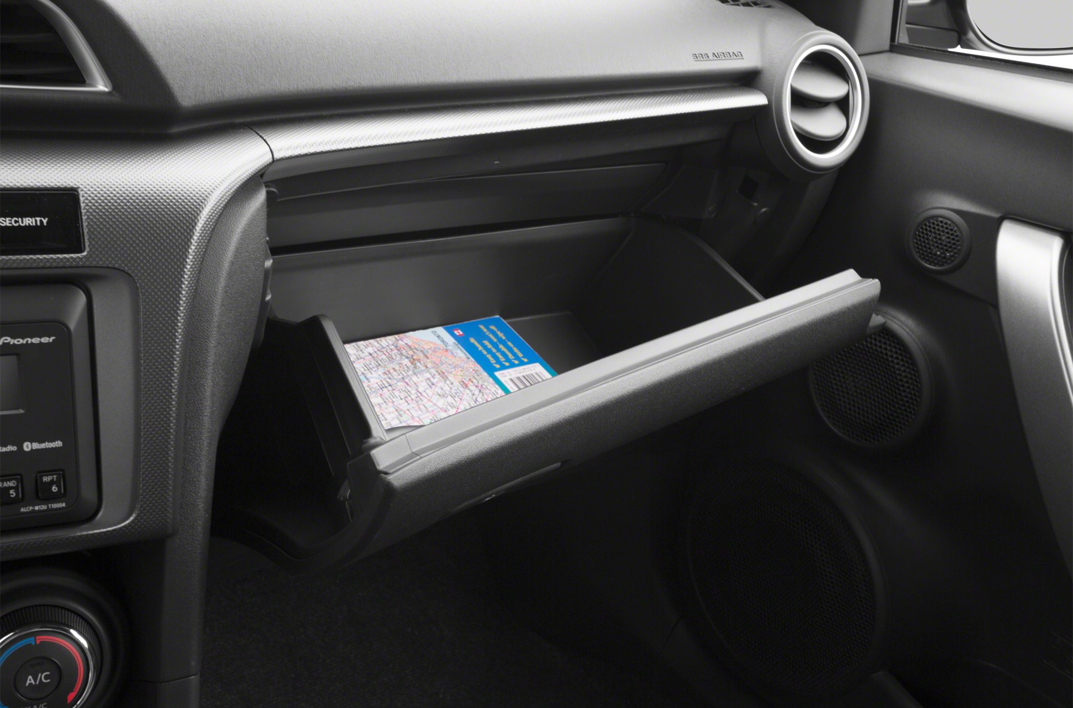 Open glove box with dashboard and round air vent in car interior