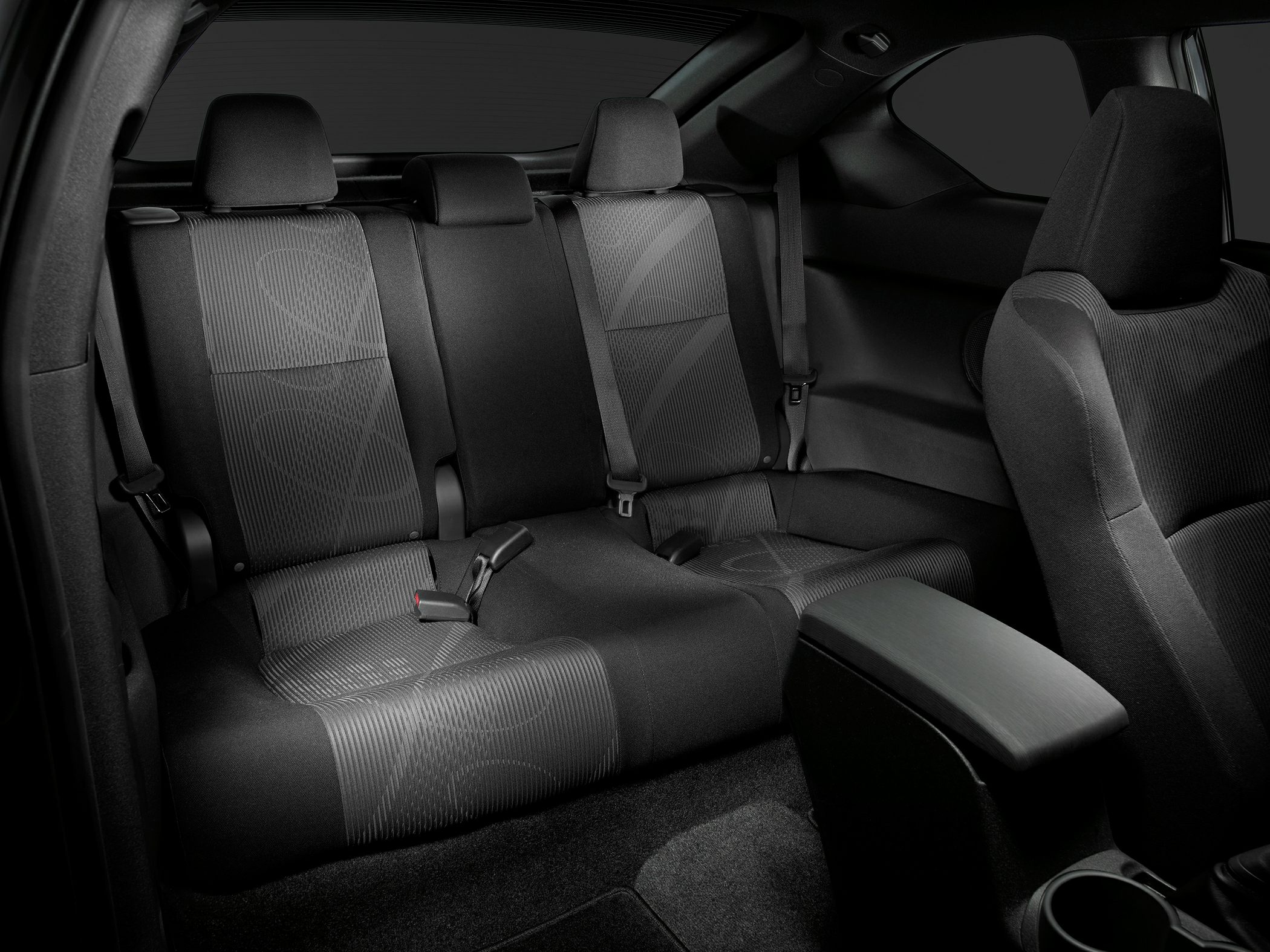 Rear seat area with patterned fabric upholstery and seat belts in a compact coupe.