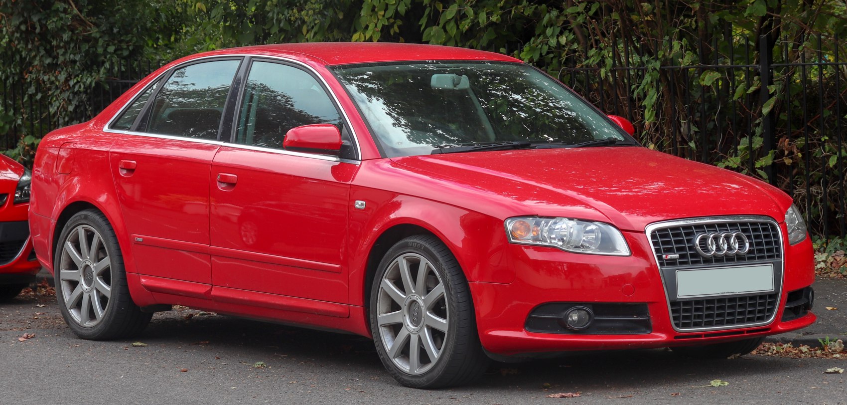 Red sedan front side view with alloy wheels and grille