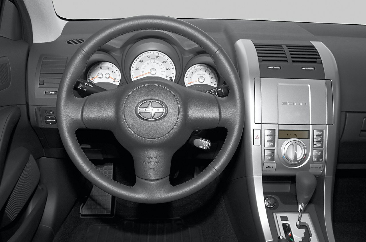 Car interior with steering wheel, instrument gauges, and center console controls
