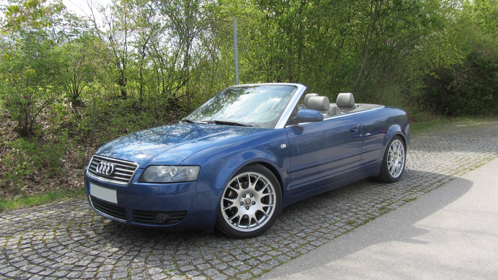Blue convertible with open roof and alloy wheels, front side perspective