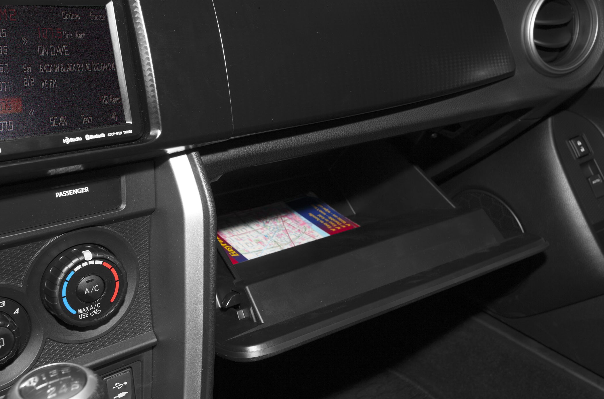 Open glove compartment and dashboard controls with air vent and climate knob