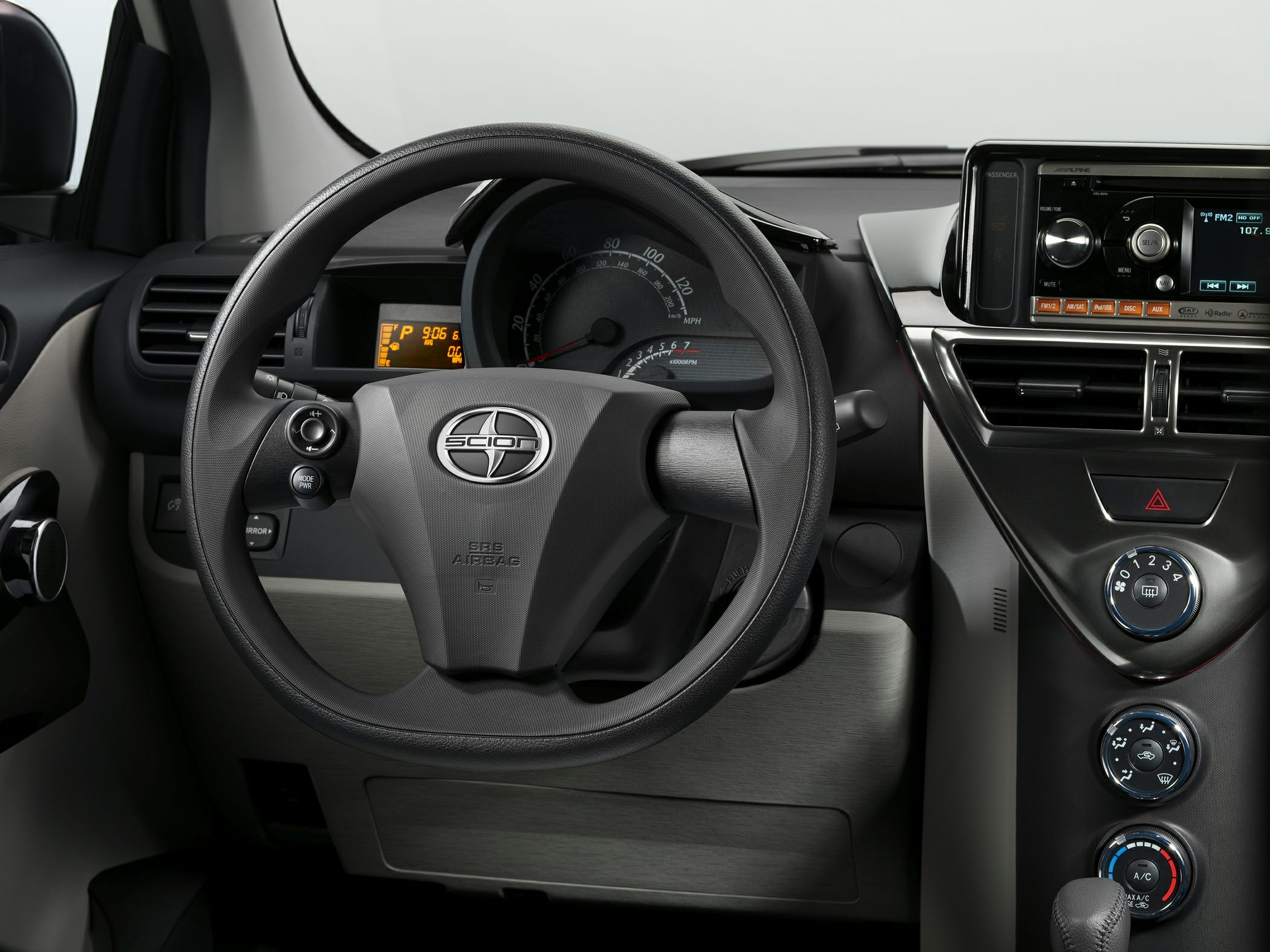 Steering wheel, dashboard, and center console controls of a compact car.