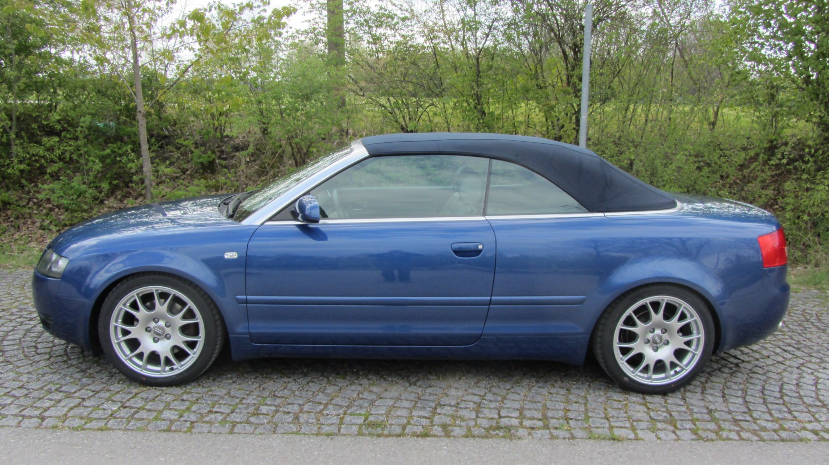 Convertible with black fabric roof and silver multi-spoke wheels side profile