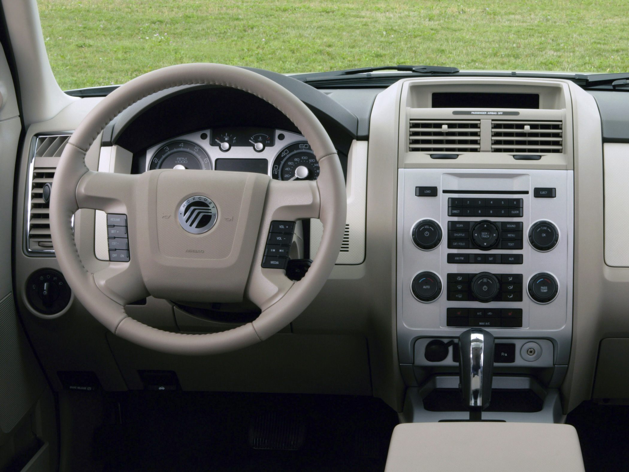Beige steering wheel and dashboard controls with central climate and media panel.