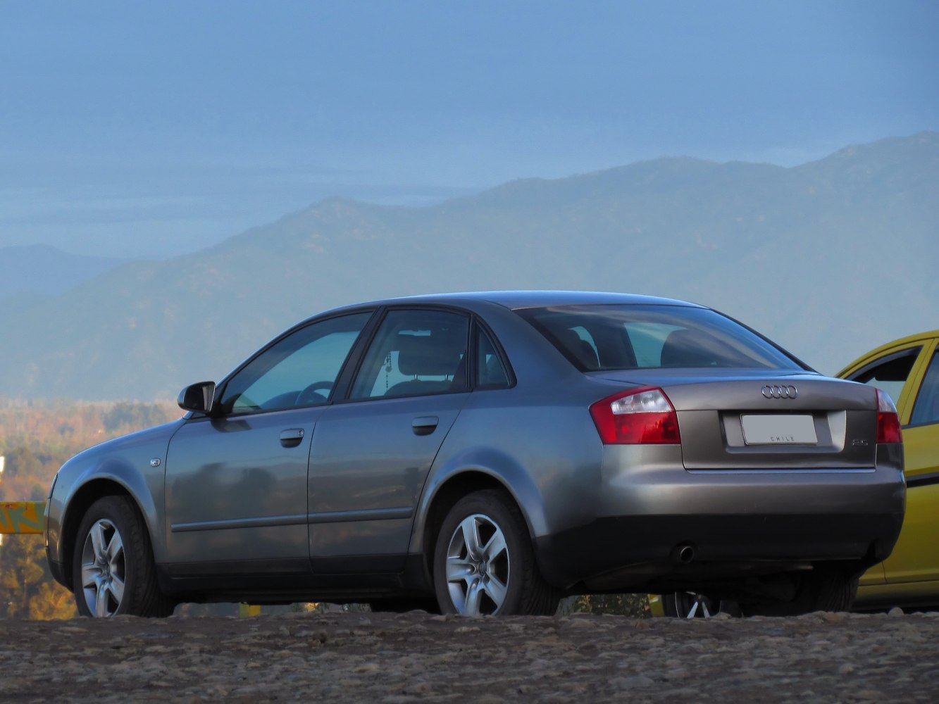 Rear and side view of mid-size sedan with alloy wheels in natural setting