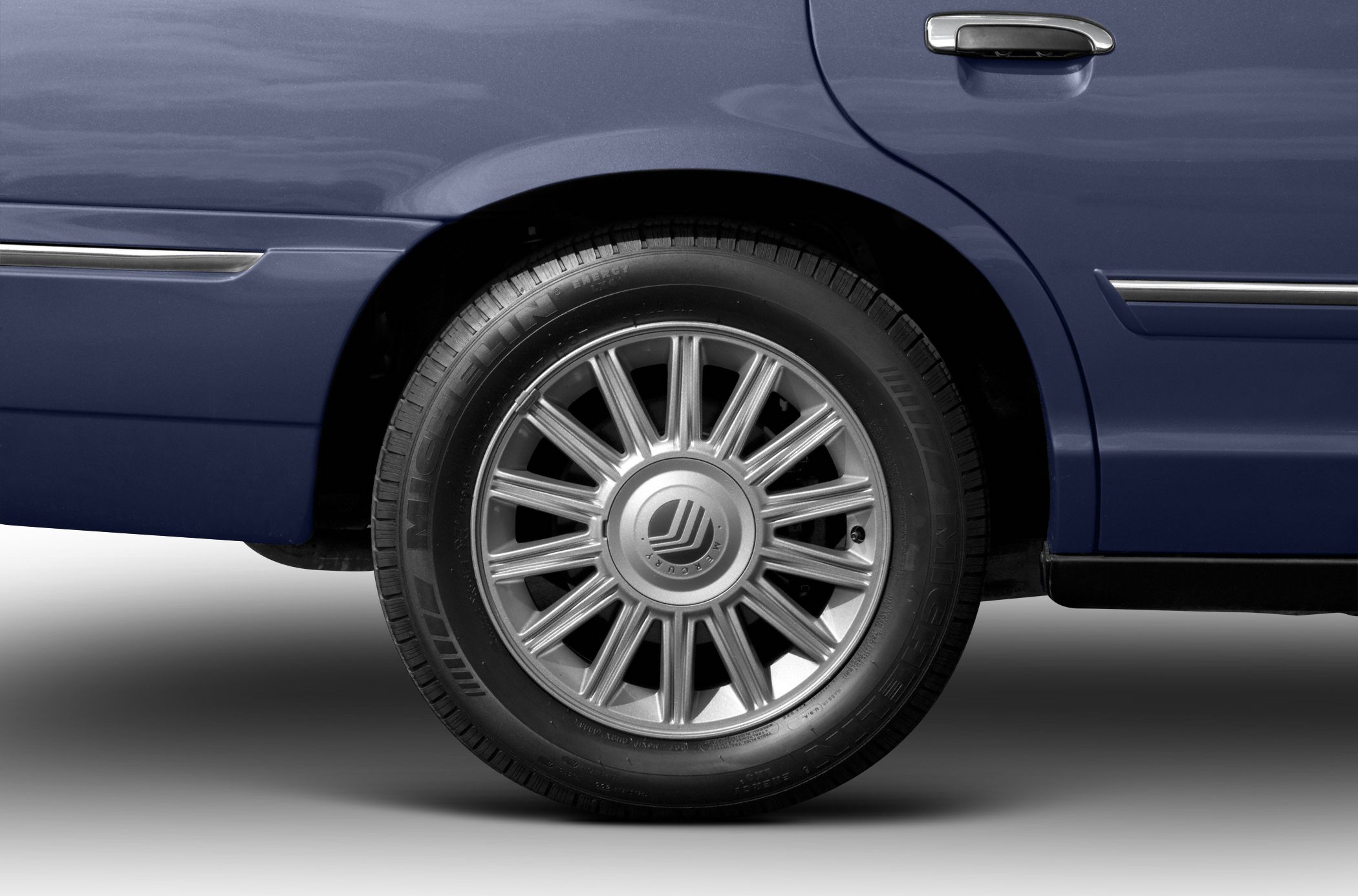 Rear wheel with alloy rim and chrome door handle of a vehicle side panel.