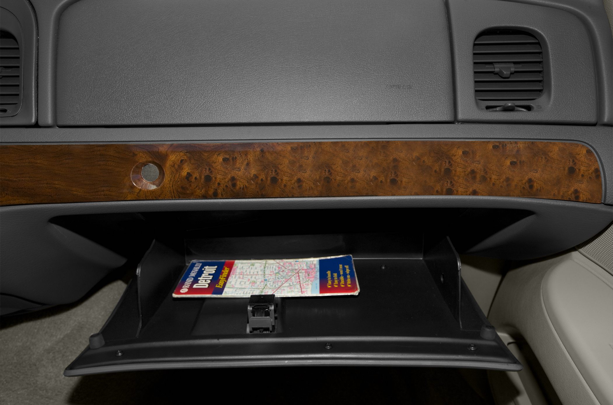 Open glove compartment with wood trim and a map inside